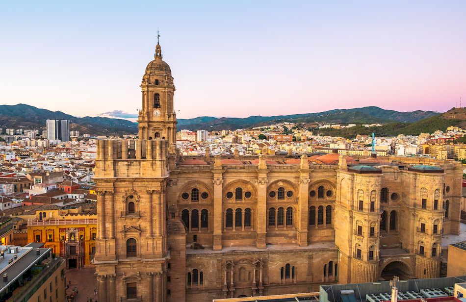Malaga Cathedral with surrounding city skyline at dusk in Malaga, Spain